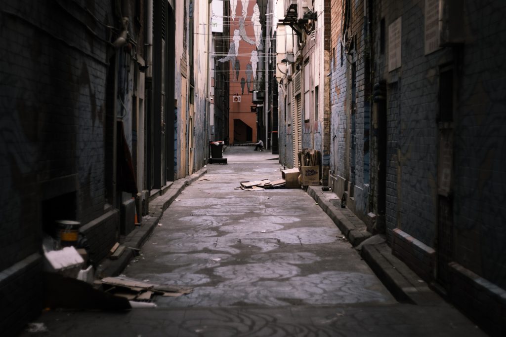 A narrow alley in a city with a building in the background.