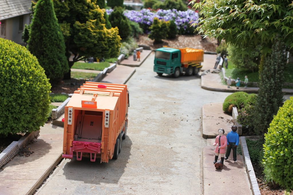 A toy truck driving down a street next to a couple of trees