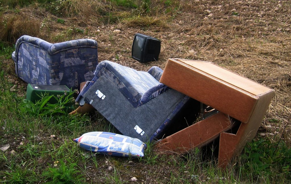 A couch and TV sitting in a field.
