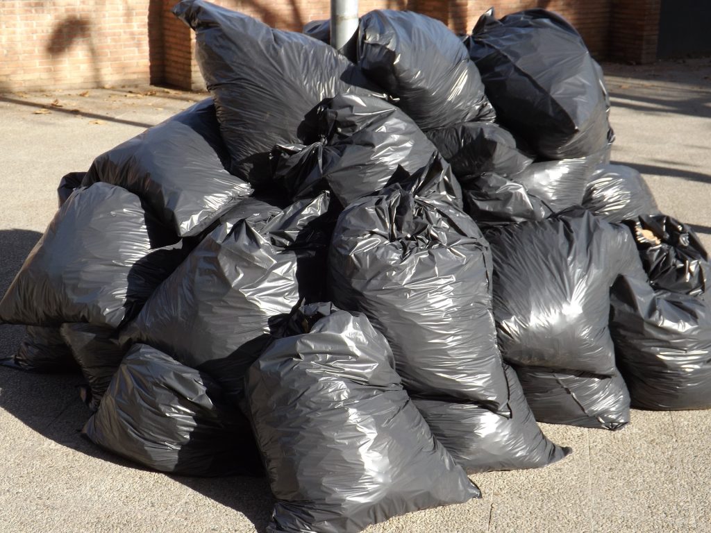 A pile of black garbage bags in front of a building.