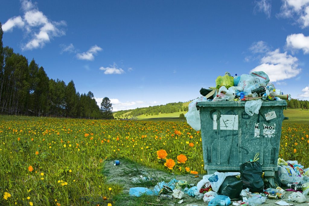 A trash can in the middle of a field.