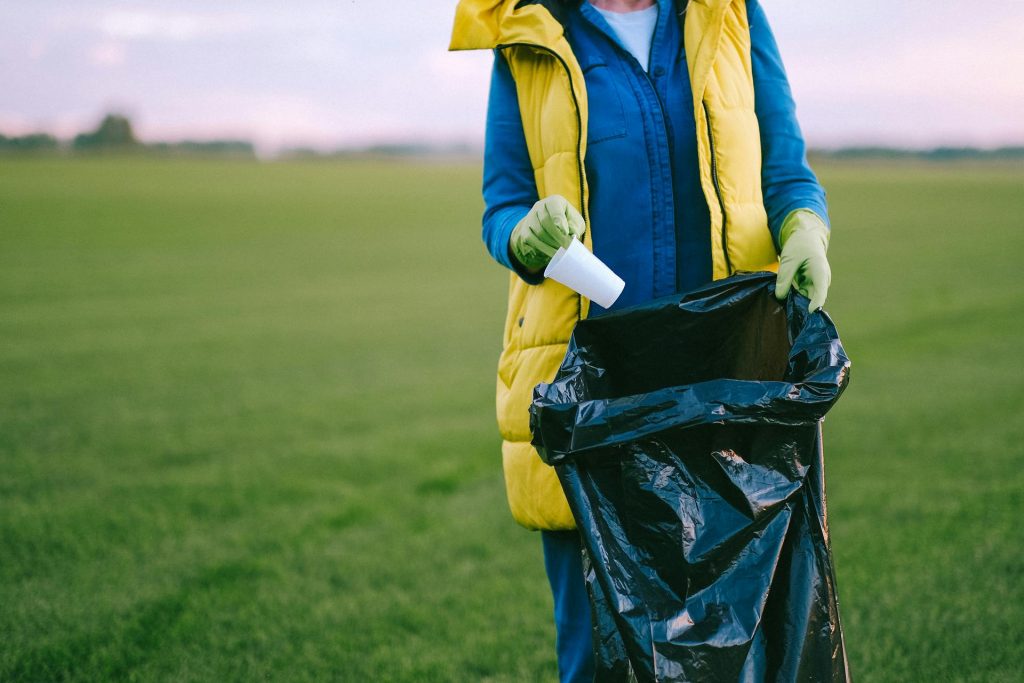 A woman standing in a field holding a rubbish bag