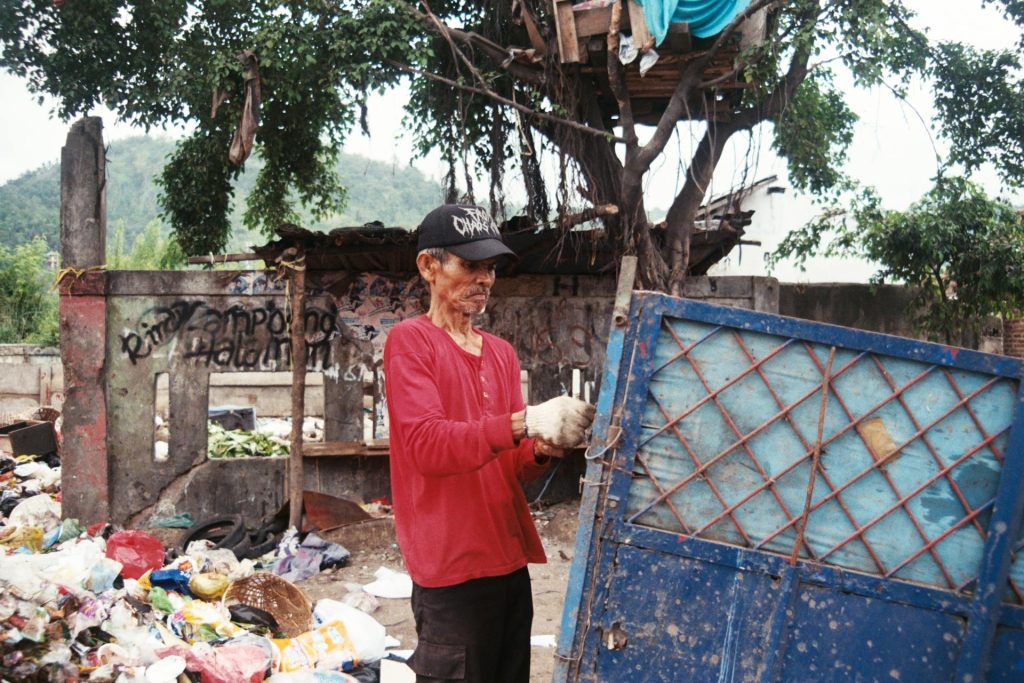 A man standing next to a pile of rubbish