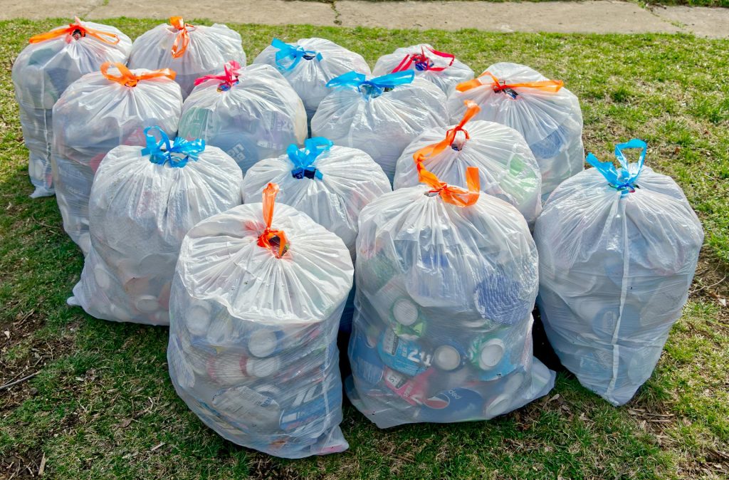 A bunch of bags of garbage sitting on the grass