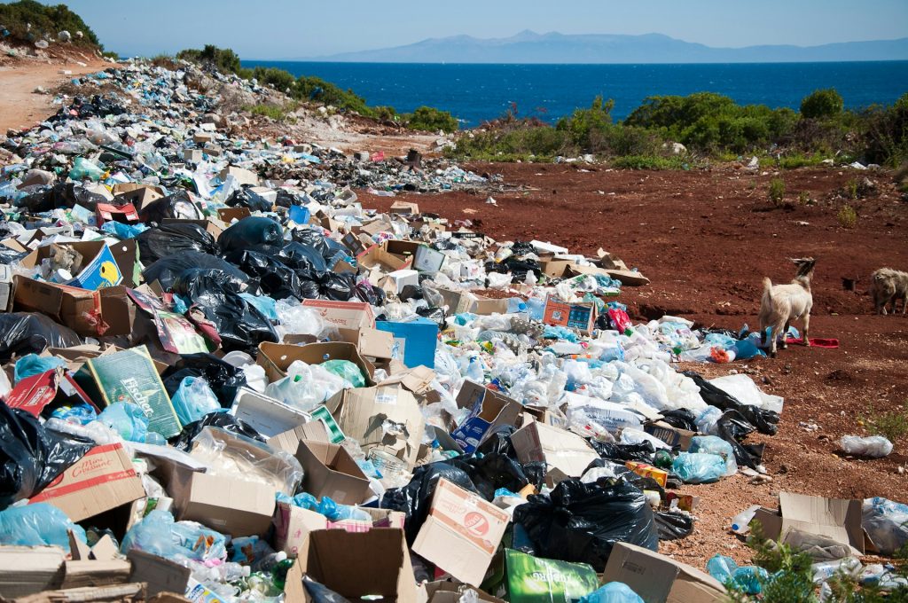 A large pile of mixed waste on a coastline, highlighting the need for cleanup and recycling services.