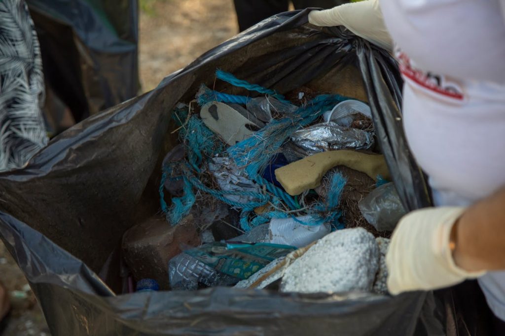 a person holding a black bag full of rubbish and waste